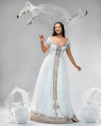 Woman in a white gown with intricate designs on a gray background