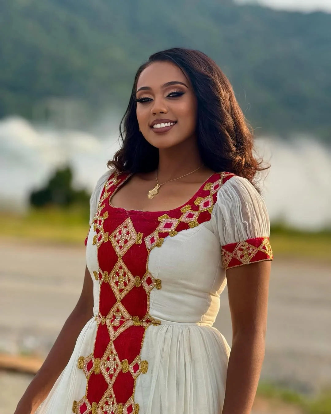 Woman wearing a traditional outfit with red and white patterns against a blurred natural background