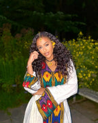 Woman in a colorful traditional outfit with a blurred natural background axum habesha kemis ethgebya