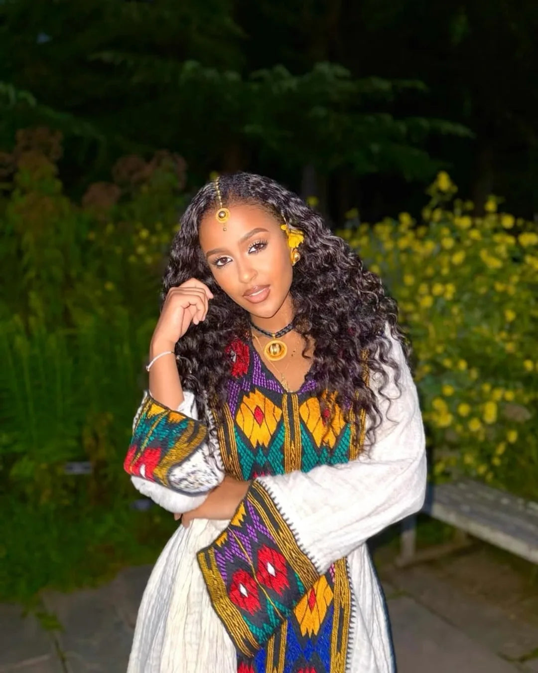 Woman in a colorful traditional outfit with a blurred natural background axum habesha kemis ethgebya