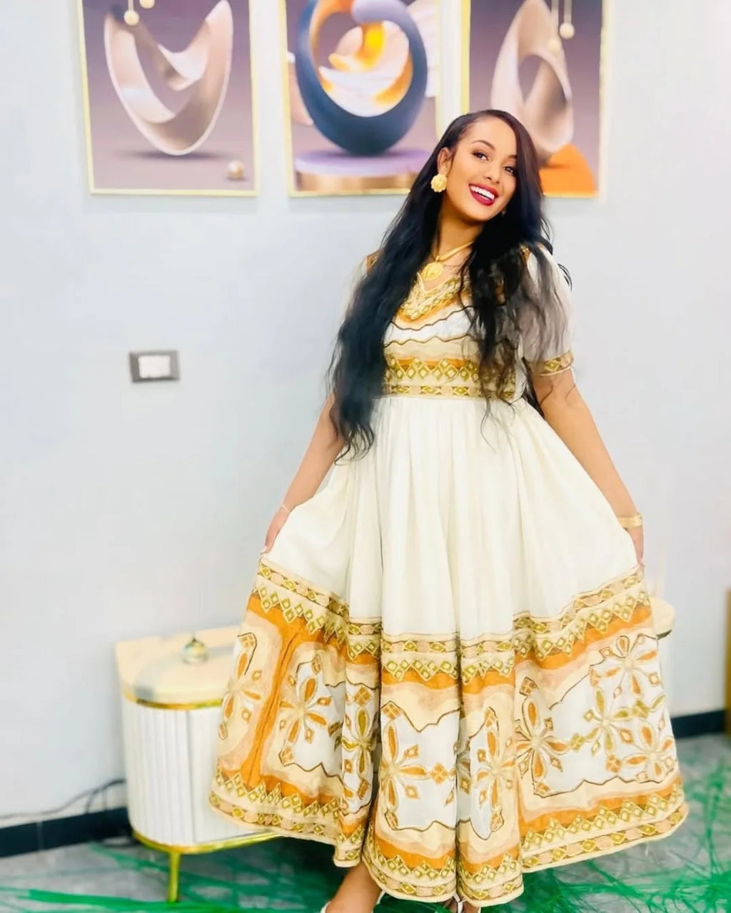 Woman wearing a white dress with gold patterns in an indoor setting Modern Zuria Kemis ethgebya