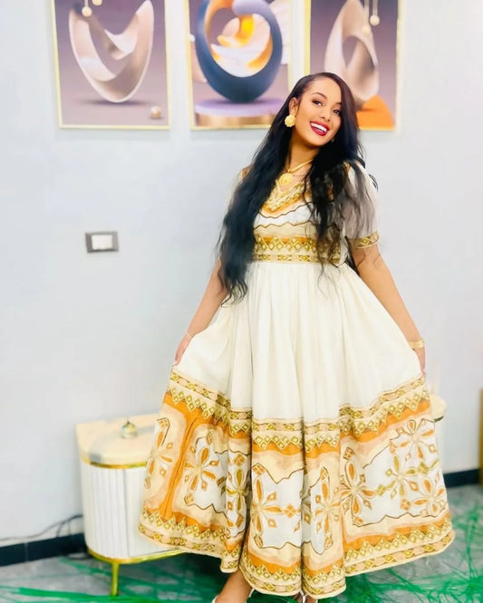Woman wearing a white dress with gold patterns in an indoor setting Modern Zuria Kemis ethgebya