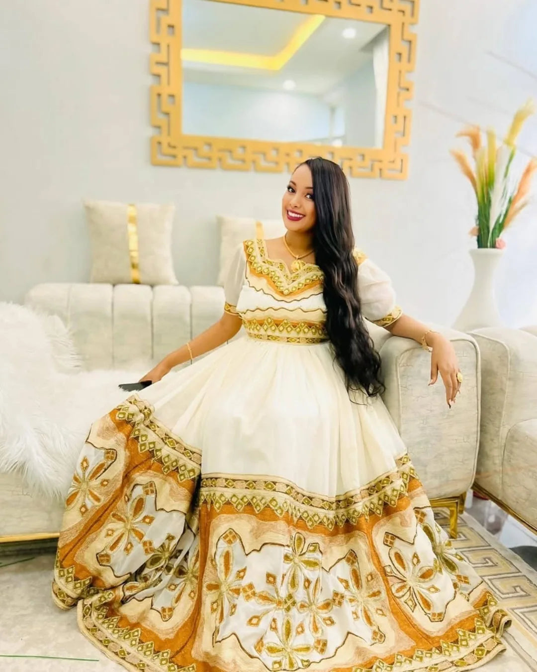 Woman in a white and gold dress sitting on a couch in a decorated Modern Zuria Kemis ethgebyaroom.