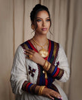 Woman wearing traditional attire with jewelry against a beige curtain background. Elegant Ethiopian & Eritrean Axum Habesha Dress Ethgebya