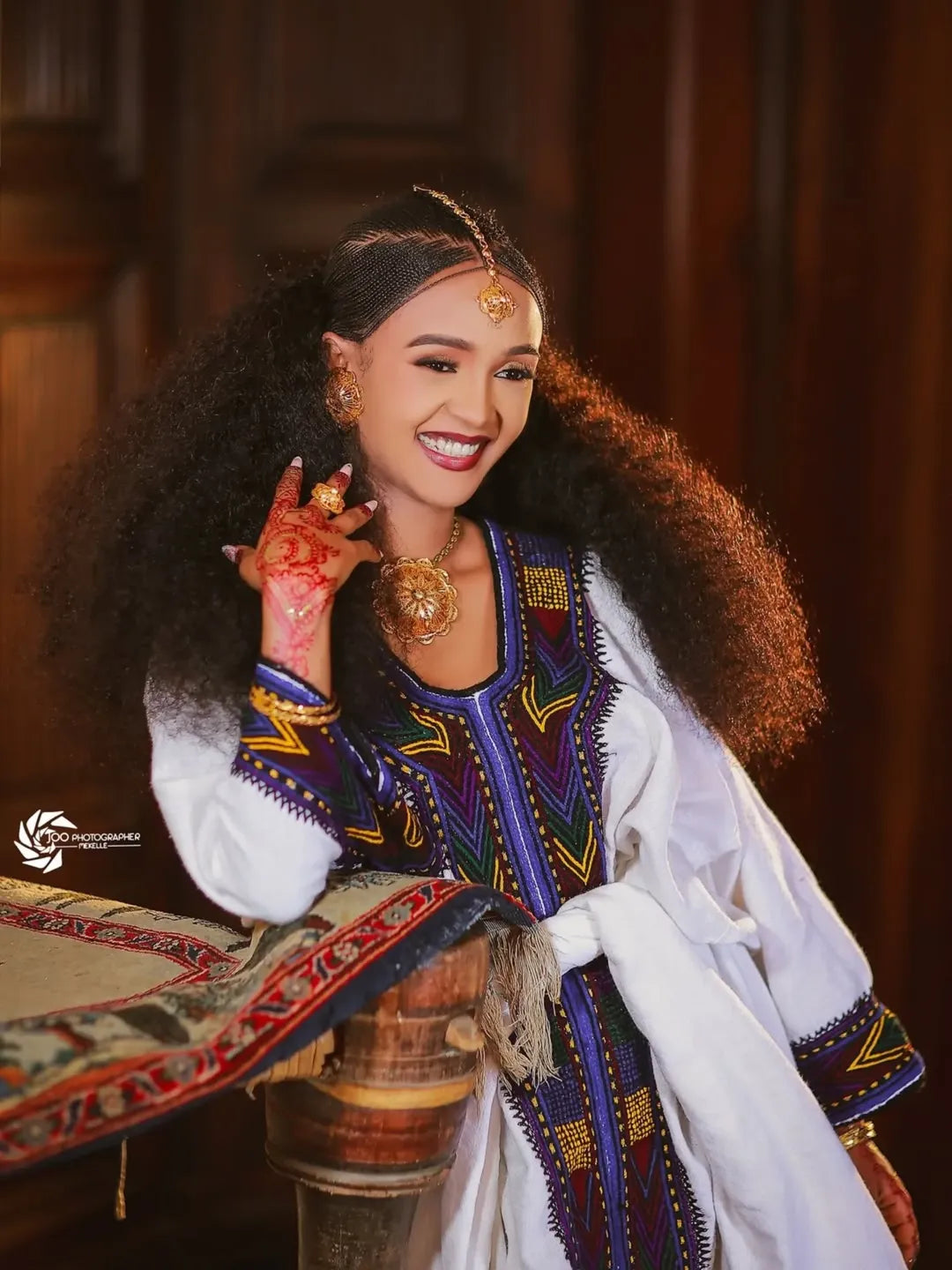 Woman in traditional attire with intricate jewelry and a decorative background. New Ethiopian & Eritrean Axum Habesha Dress Handwoven Tilet Kemis Ethiopia Gebeya Ethgebya