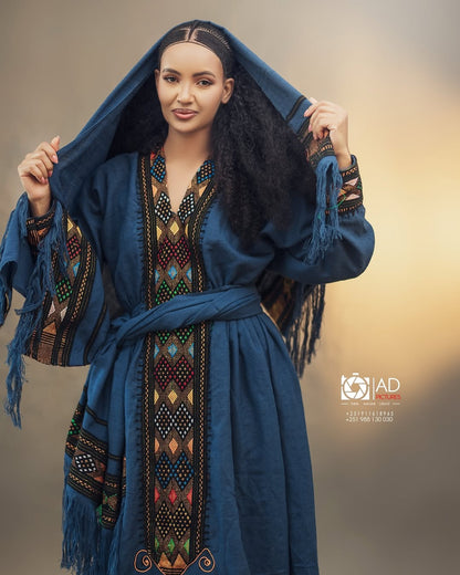 Woman wearing a blue embroidered dress with a hood against a neutral background Dark Blue Raya Cultural Dress Handwoven Ethiopian Habesha Kemis ethgebya gebeya usa habesha kemis