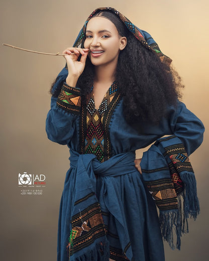 Woman in traditional attire with a decorative headscarf against a beige background Dark Blue Raya Cultural Dress Handwoven Ethiopian Habesha Kemis ethgebya gebeya usa habesha kemis
