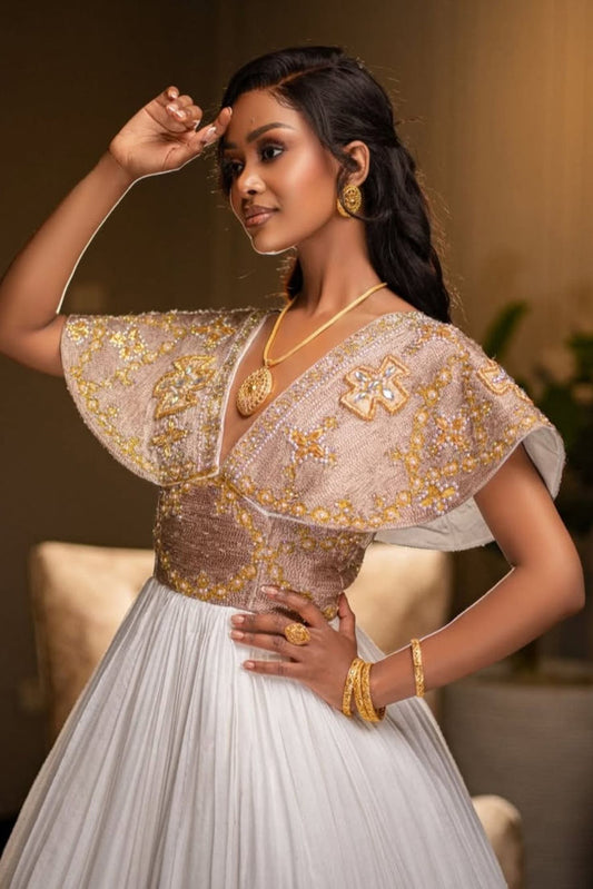 Woman wearing an ethiopian traditional outfit with gold embroidery and jewelry against a blurred background