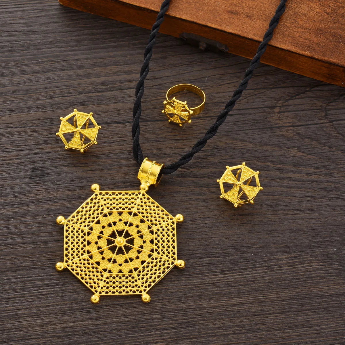 Gold jewelry set with necklace, earrings, and ring on a wooden surface
