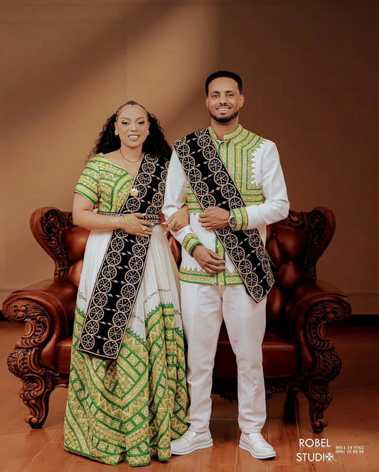 Couple in traditional attire standing in front of a brown background with a visible brand logo.  ethiopian and eritrean ethgebya