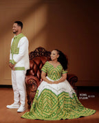 Man and woman in traditional green and white attire posing in a room with a wooden chair. ethiopian and eritrean ethgebya