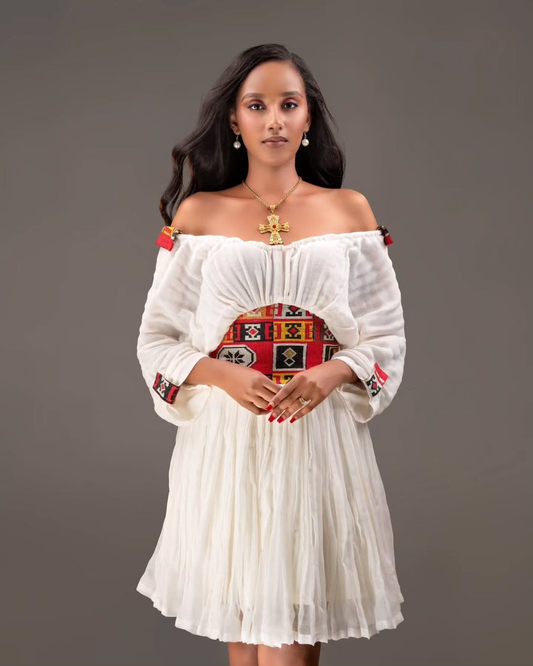 Woman wearing a white off-shoulder dress with colorful patterns on a gray background Red Tilet Habesha Short Kemis New Modern Ethiopian Dress ethgebya gebeya