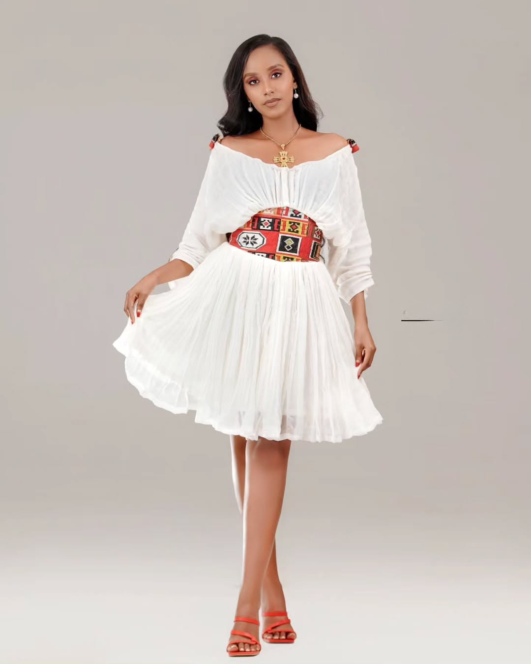 Woman wearing a white dress with a colorful belt on a light gray background Red Tilet Habesha Short Kemis New Modern Ethiopian Dress ethgebya gebeya