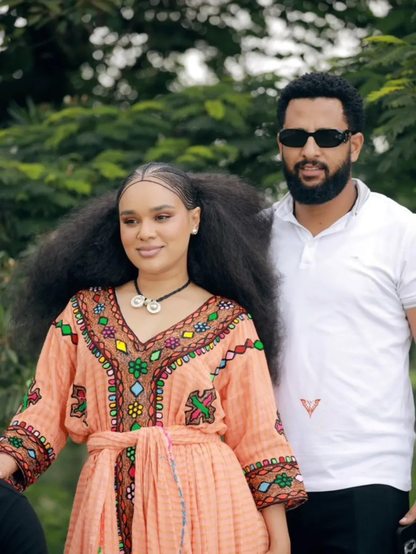 Two people standing outdoors with a blurred green background Gold Sand Ethiopian & Eritrean Axum Habesha Dress Ethgebya