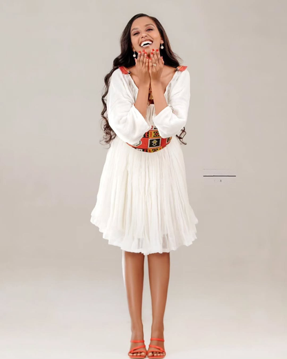 Woman wearing a white dress with a colorful belt on a plain background Red Tilet Habesha Short Kemis New Modern Ethiopian Dress ethgebya gebeya