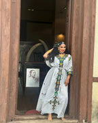 Woman in a long, patterned dress standing in a doorway.