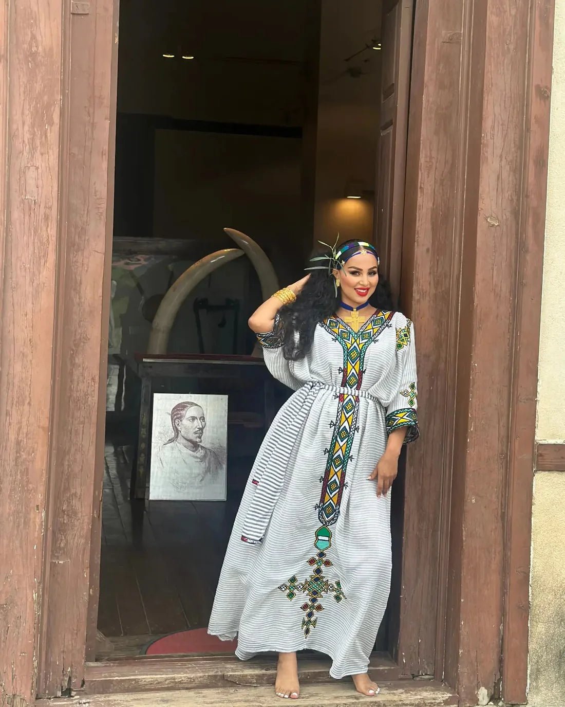 Woman in a long, patterned dress standing in a doorway.