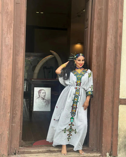 Woman in a long, patterned dress standing in a doorway.