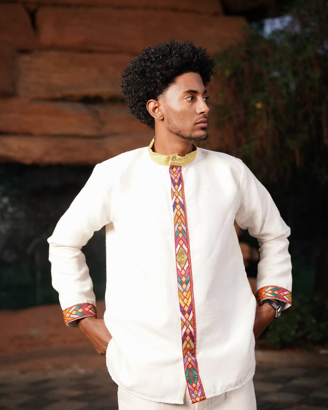 Man wearing a traditional outfit with colorful patterns in an outdoor setting Modern Habesha Men’s Shirt New Elegant Ethiopian Traditional Wear ethgebya gebeya