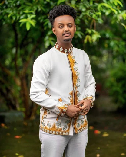 Man wearing a traditional outfit with white and gold patterns in a natural setting