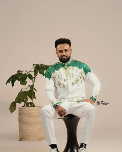 Man in a green and white outfit sitting on a black stool with a plant in the background Green Luxury Habesha Men’s Shirt New Modern Ethiopian Attire ethgebya gebeya usa habesha
