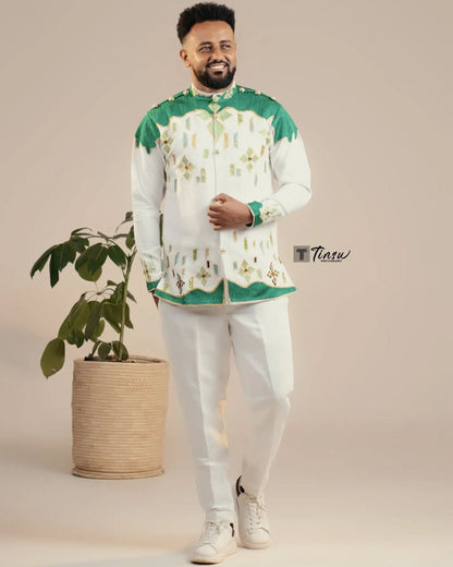 Man wearing a traditional outfit with green and white patterns, standing next to a potted plant on a beige background. Green Luxury Habesha Men’s Shirt New Modern Ethiopian Attire ethgebya gebeya usa habesha