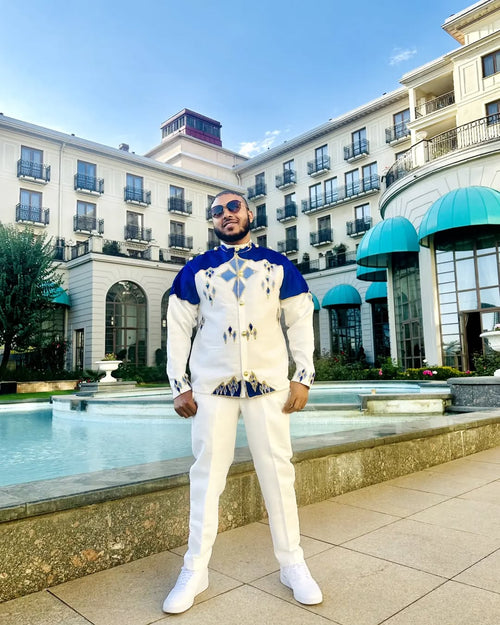 Man in a stylish outfit standing in front of a building with a pool. Blue Habesha Men’s Shirt New Modern Ethiopian Traditional Wear ethgebya gebeya usa habesha mens
