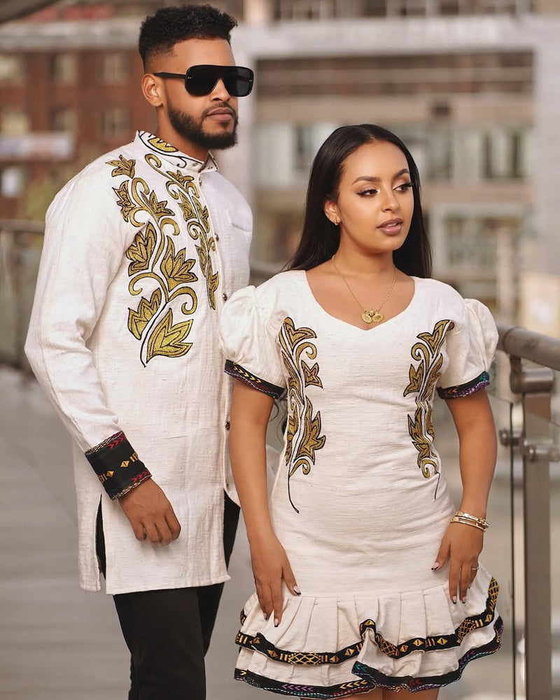 Man and woman in traditional embroidered outfits standing outdoors. Modern Ethiopian Couple Set Mini Dress & Men’s Habesha Shirt ethgebya gebeya usa habesha kemis mini