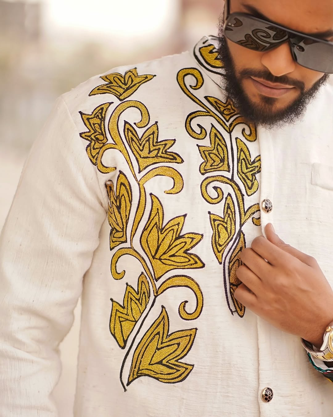 Man wearing a white embroidered jacket with gold patterns and sunglasses. Modern Ethiopian Couple Set Mini Dress & Men’s Habesha Shirt ethgebya gebeya usa habesha kemis mini