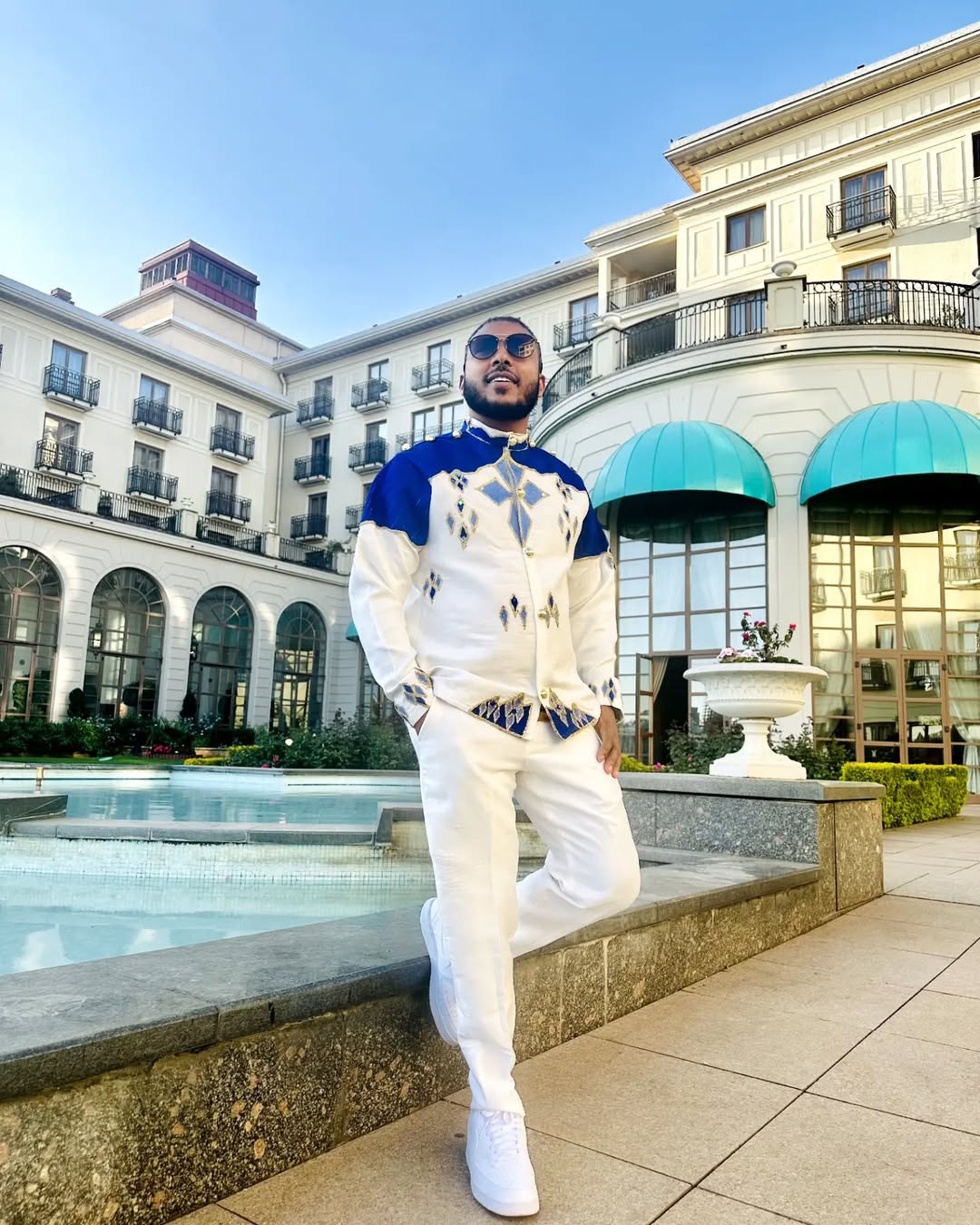 Man in a stylish outfit standing in front of a building with a pool Blue Habesha Men’s Shirt New Modern Ethiopian Traditional Wear ethgebya gebeya usa habesha mens