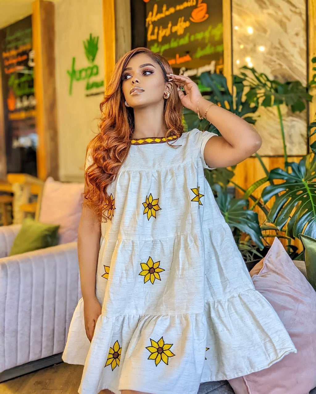 Woman in a white dress with yellow floral patterns in a casual indoor setting Lightweight Short Habesha Dress Modern Summer Ethiopian Kemis ethgebya gebeya habesha kemis usa