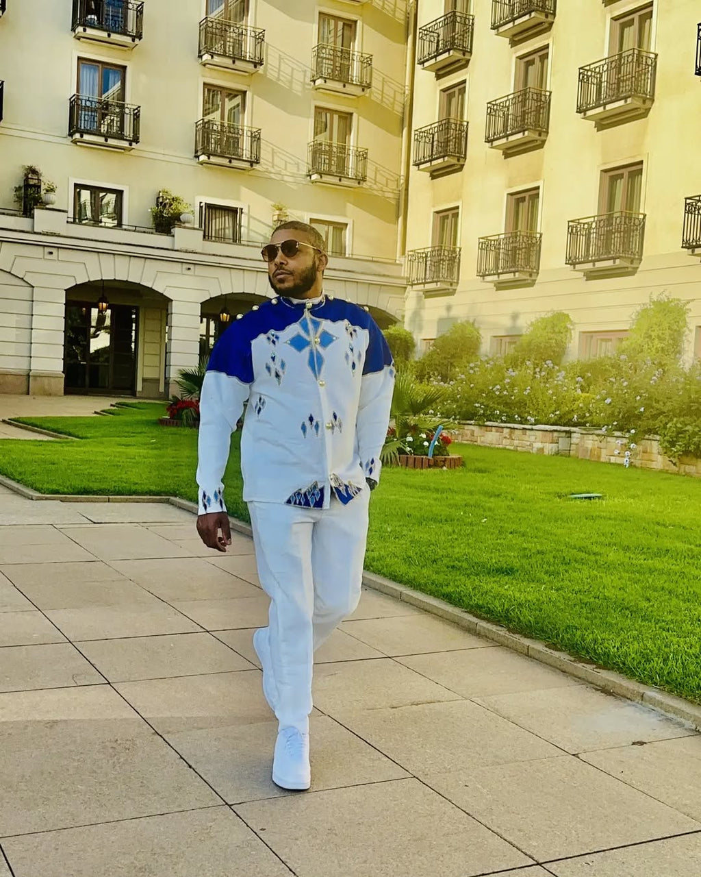 Man walking in a courtyard with a building in the background Blue Habesha Men’s Shirt New Modern Ethiopian Traditional Wear ethgebya gebeya usa habesha mens