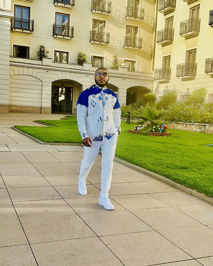 Man in a white outfit with blue accents standing in front of a building with balconies. Blue Habesha Men’s Shirt New Modern Ethiopian Traditional Wear ethgebya gebeya usa habesha mens