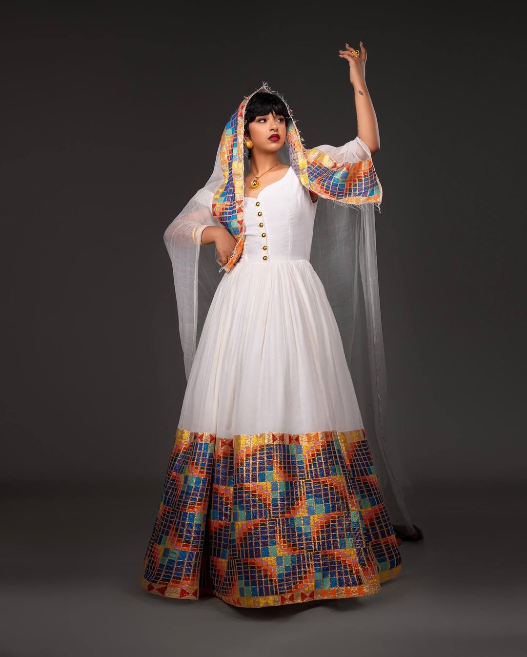 Woman wearing a white dress with colorful patterns and a headscarf on a dark background. Open-Back Modern Zuria Habesha Kemis Elegant Ethiopian Dress ethgebya gebeya usa habesha kemis