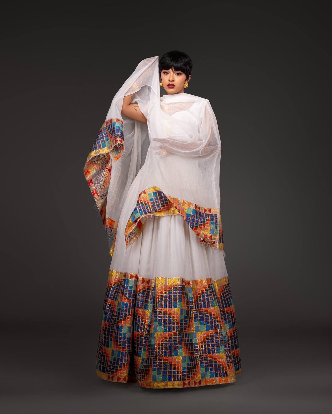 Woman wearing a white outfit with a colorful patterned dupatta against a dark background Open-Back Modern Zuria Habesha Kemis Elegant Ethiopian Dress ethgebya gebeya usa habesha kemis