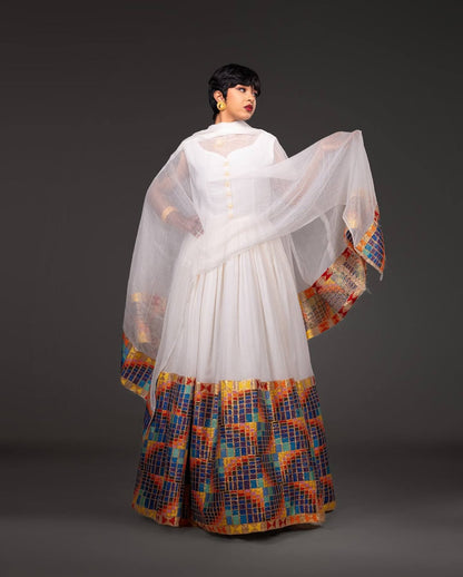 Woman wearing a white top with a colorful, patterned skirt against a dark background Open-Back Modern Zuria Habesha Kemis Elegant Ethiopian Dress ethgebya gebeya usa habesha kemis