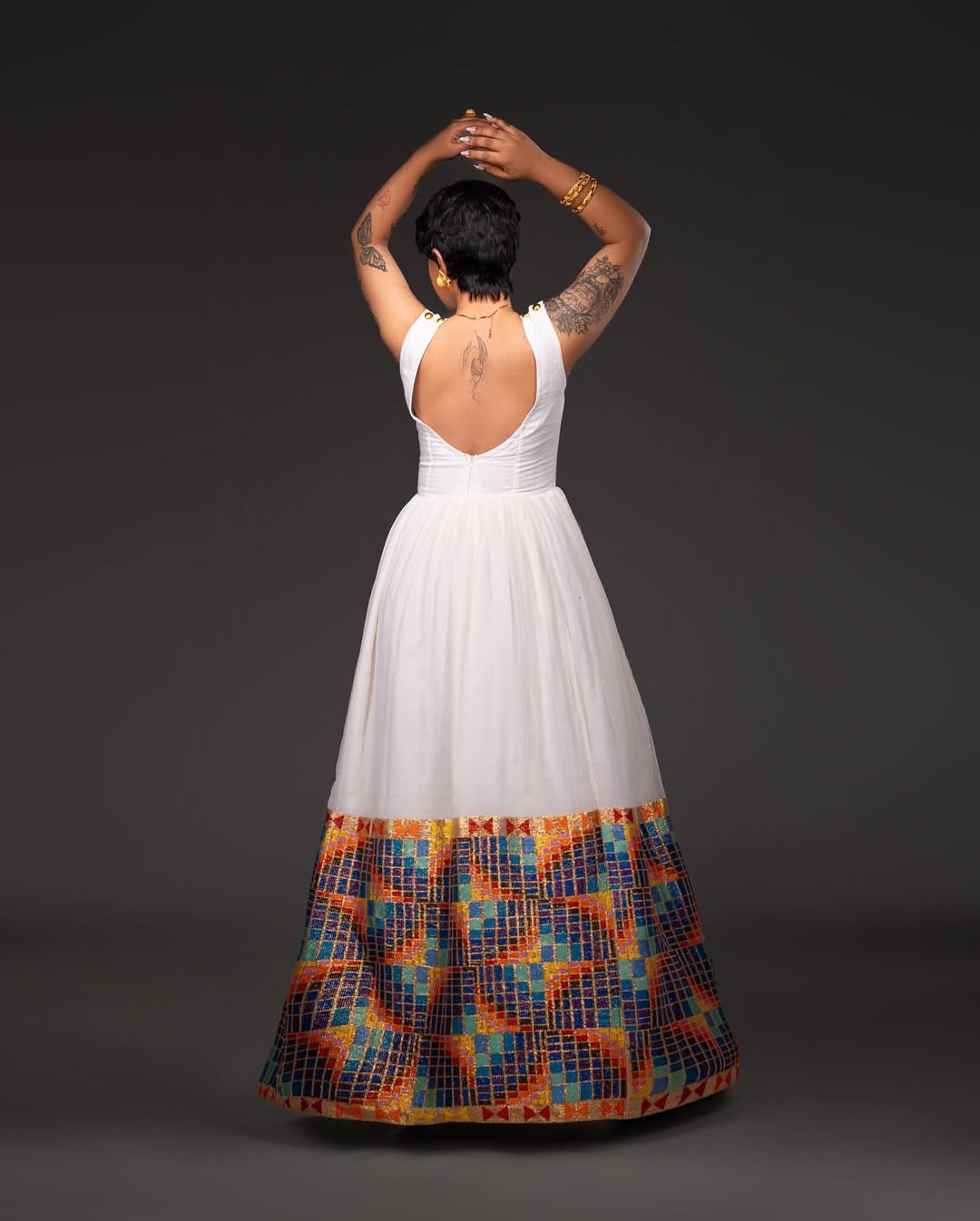 Person wearing a white dress with a colorful patterned bottom half on a dark background Open-Back Modern Zuria Habesha Kemis Elegant Ethiopian Dress ethgebya gebeya usa habesha kemis