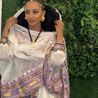 Woman in traditional attire with colorful patterns against a green leafy background Rose Gold Zuria Habesha Kemis Modern Ethiopian Traditional Dress ethgebya gebeya usa habesha kemis