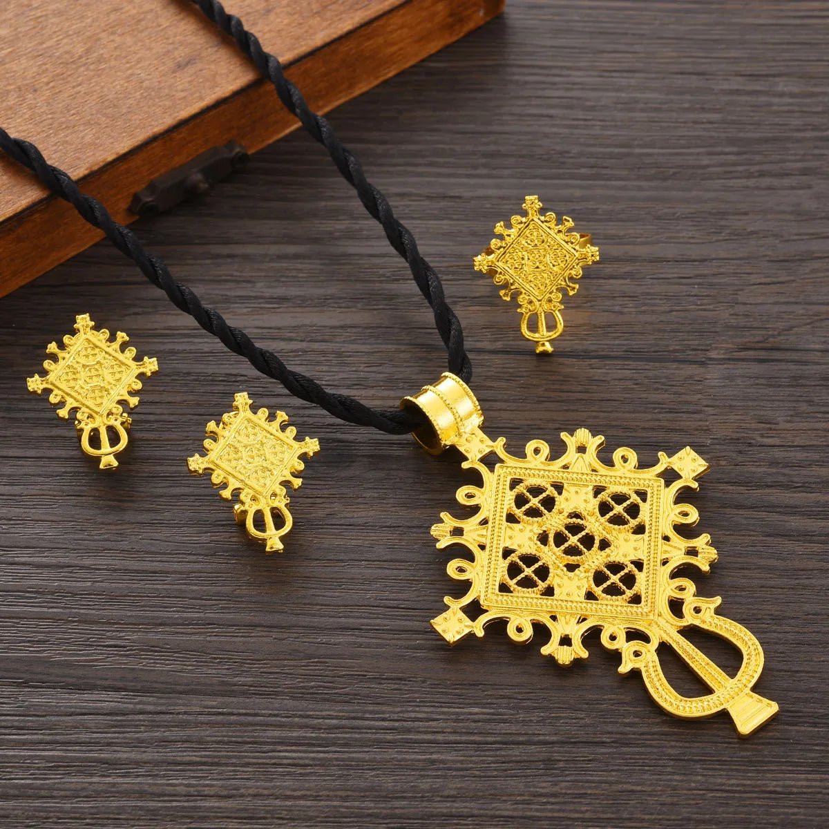 Gold necklace and earrings set on a wooden surface