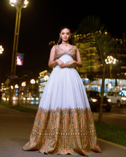 Woman in a white and patterned dress standing on a street at night.