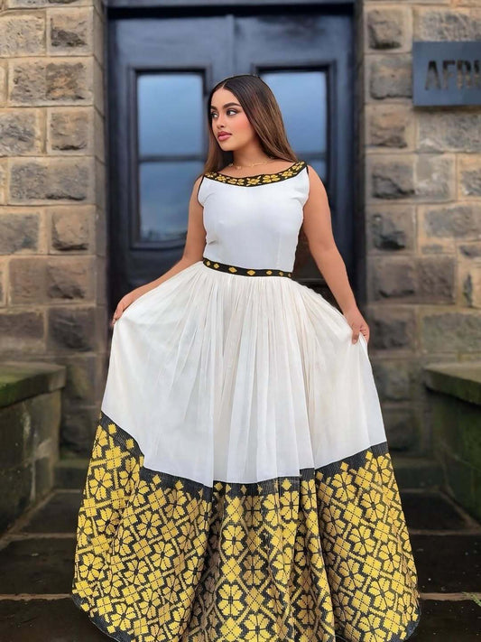 Woman wearing a white top with black and gold accents and a yellow floral skirt in front of a stone building.