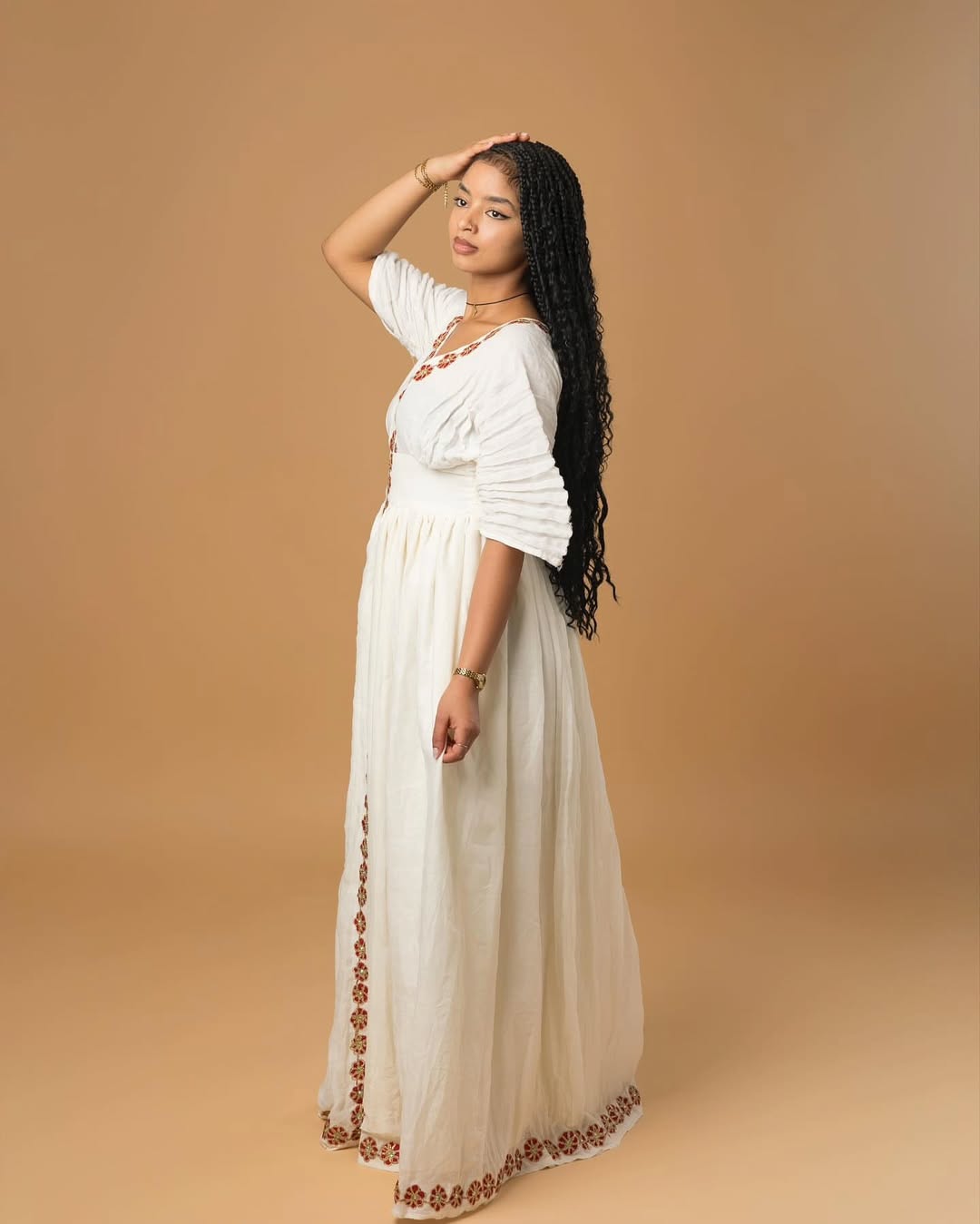 Woman wearing a white dress with brown embellishments on a beige background Red Flower Zuria Habesha Kemis Modern Ethiopian Traditional Dress ethgebya simple habesha kemis gebeya