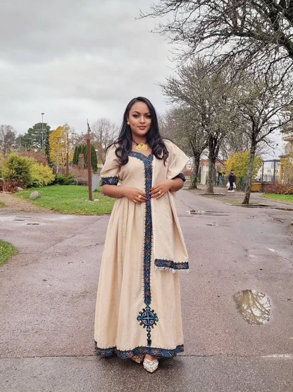 Woman in a long, light-colored dress with dark embellishments standing on a street. Beige Modern Zuria Habesha Kemis Stylish Ethiopian Traditional Dress ethgebya gebeya habesha kemis