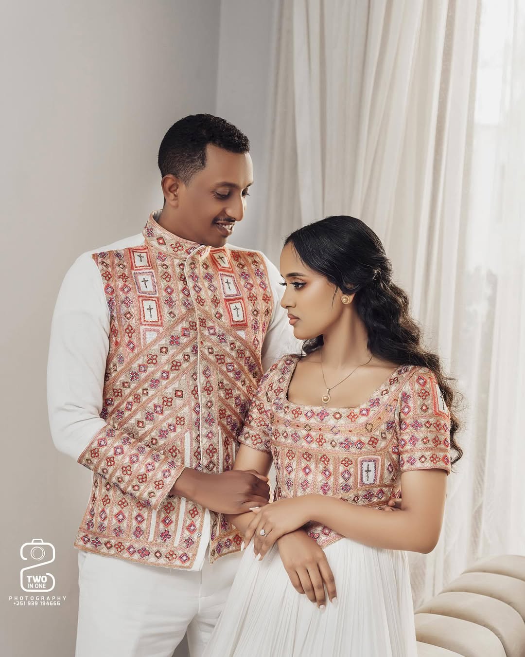 Couple in traditional attire sitting together with a neutral background. Ethiopian Brown Habesha Wedding Attire Matching Couple Set Ethgebya