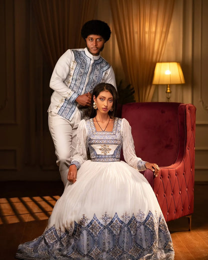 Two people in formal attire sitting on a red armchair in a dimly lit room. Blue Habesha Couple Outfit New Elegant Matching Ethiopian Attire ethgebya gebeya fikregna fiqregnoch