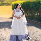 White Flowy Traditional Habesha kemis, Eritrean & Ethiopian Cultural Dress featuring Blue Embroidery Along The Hem.