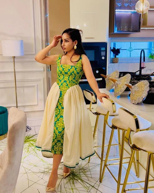 Woman in a green and white traditional outfit standing in a modern kitchen.