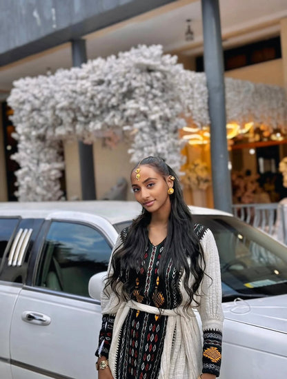 Woman standing in front of a white car with decorative flowers in the background Special Axum Habesha Kemis | Modern Ethiopian Traditional Dress