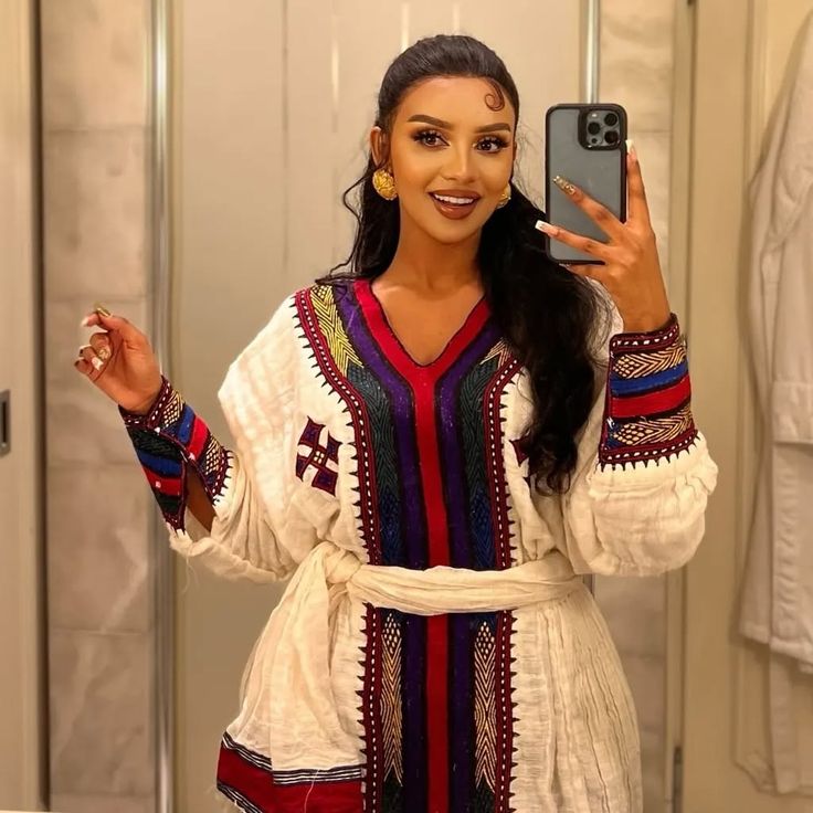 Woman taking a mirror selfie wearing a colorful traditional outfit. Elegant Ethiopian & Eritrean Axum Habesha Dress Ethgebya