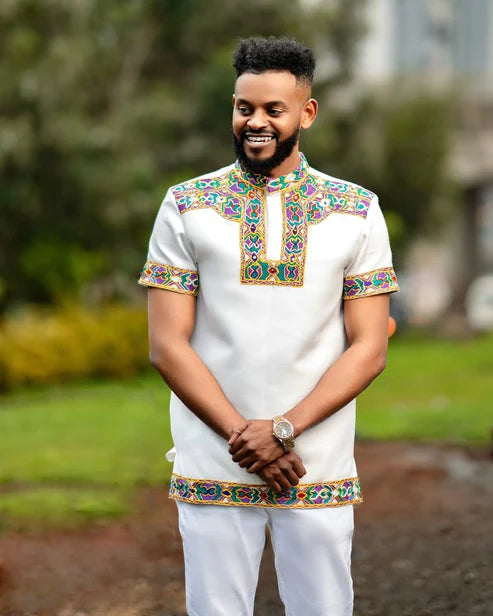 Man wearing a traditional outfit with colorful embroidery outdoors Men’s Short Sleeve Habesha Shirt White Ethiopian Traditional Wear ethgebya